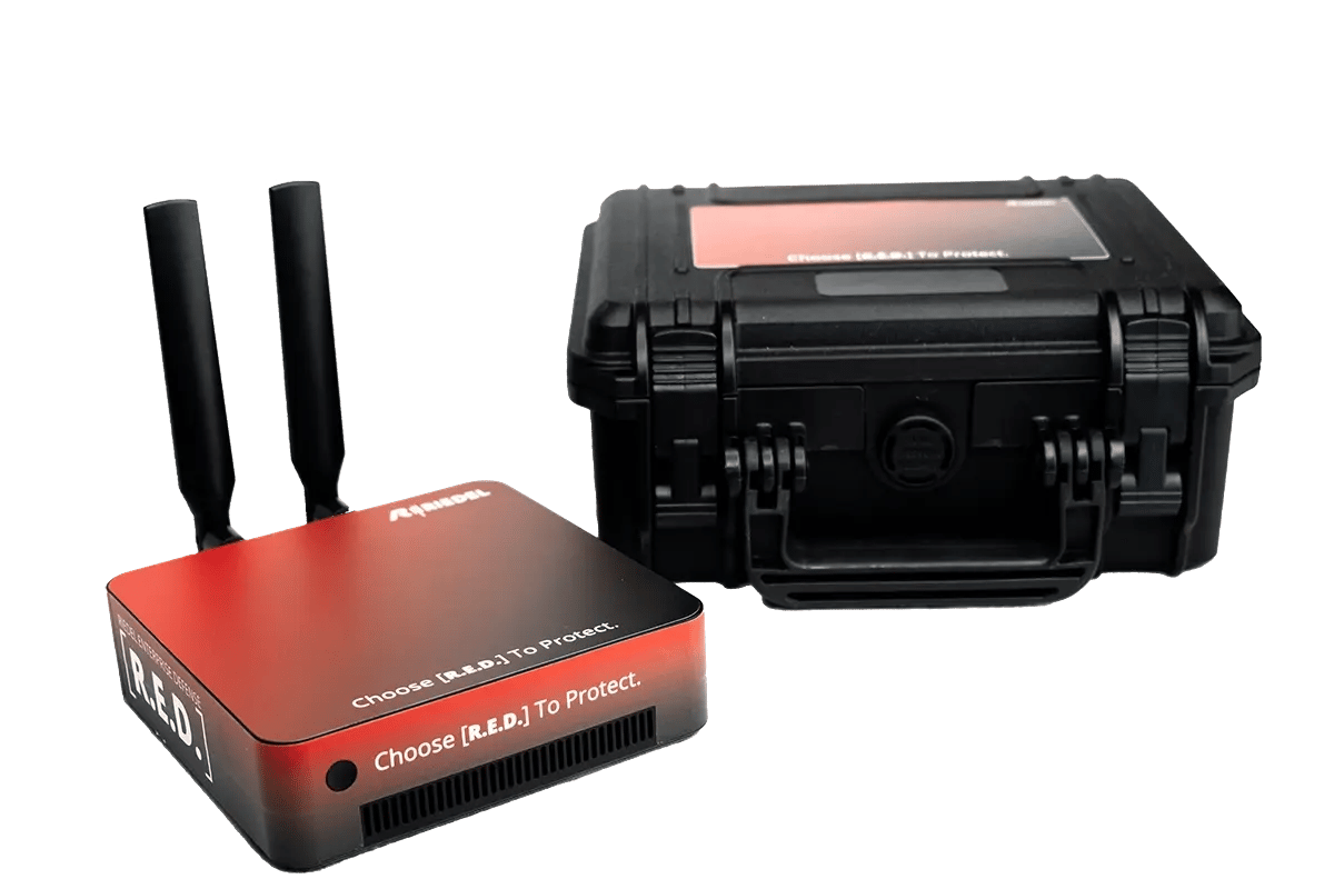 Abbildung eines RED‑Geräts von RIEDEL Networks mit zwei Antennen neben einem robusten schwarzen Transportkoffer. Das Gerät ist für sichere Netzwerk‑ und IT‑Anwendungen konzipiert und wird als kompakte Hardware‑Lösung dargestellt.